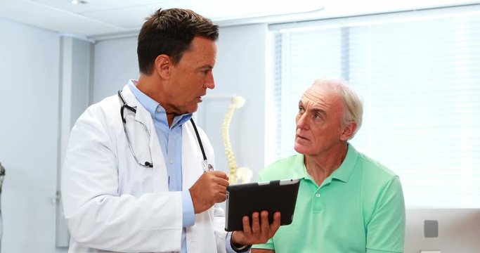 Doctor and senior patient discussing over digital tablet