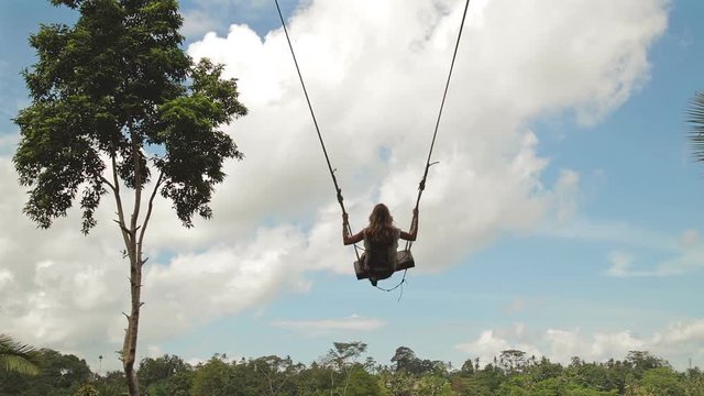 Girl swinging on a big swing in the jungle.
