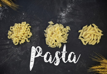 variety of pasta on wooden background with sign on it
