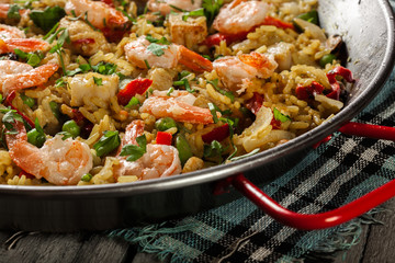 Traditional seafood paella with shrimp, fish and chicken seved in paellera