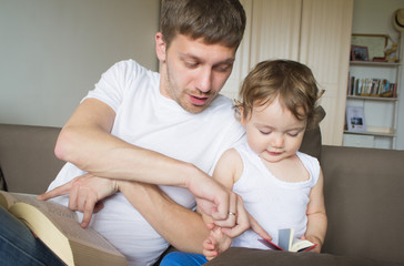 Fototapeta premium Dad is reading a book with a child. Young father. Father's Day