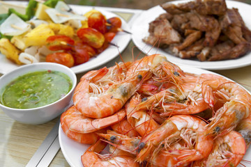 grilled or baked shrimp and pork with vegetable barbecue BBQ and seafood sauce in white dish and wood table on summer holiday picnic for dinner food