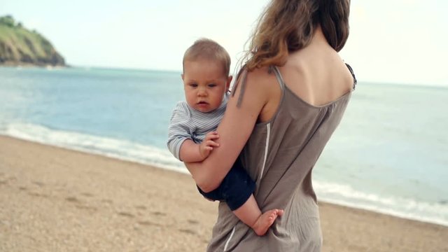 Little baby being carried by his mother on the beach