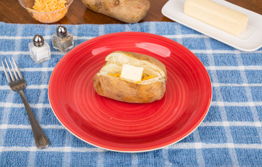 Baked Potato on Red Plate with Butter and Cheese