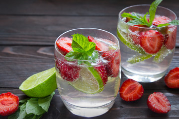 Cold summer drinks in glasses with strawberry , lime and mint