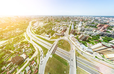 Aerial city view with crossroads and roads, houses, buildings, parks and parking lots, bridges. Helicopter drone shot. Wide Panoramic image.