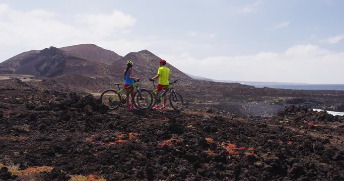 Mountain biking MTB cyclists woman and man resting enjoying view on recreational bike trip Mountain biker couple riding bicycle enjoying healthy lifestyle in nature, Lanzarote, Canary Islands, Spain