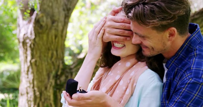 Man covering woman eyes while giving her surprise gift