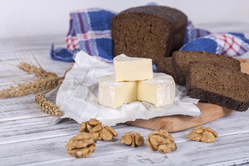 Brie type of cheese. Camembert cheese. Fresh Brie cheese and a slice on a wooden board with black bread slice. Italian, French cheese.