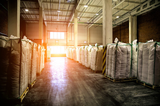 Hangar warehouse with big white polyethylene bags of industrial and logistics companies. Warehousing on the floor