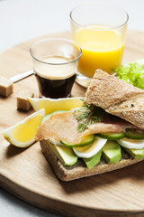 Rye bread sandwich with avocado, eggs, cucumber and smoked salmon
