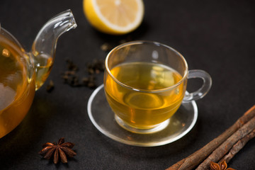 Cup of ginger tea with lemon and honey on dark stone background