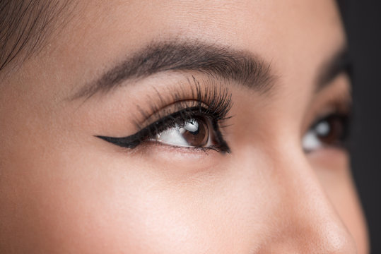Perfect shape of eyebrows. Beautiful macro shot of female eye with classic eyeliner makeup.