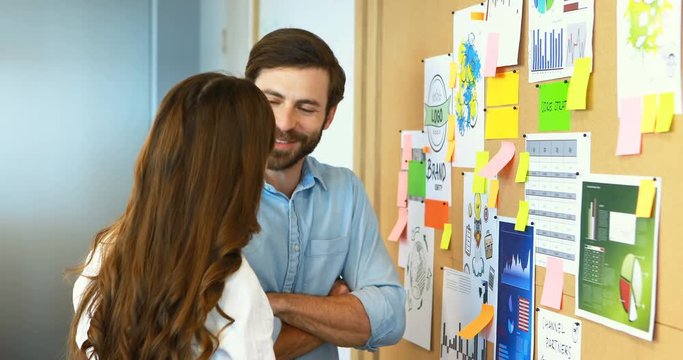 Business colleagues interacting with each other near bulletin board