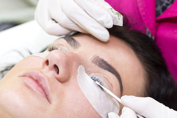 Obraz na płótnie Canvas Woman on the procedure for eyelash extensions, eyelashes lamination 