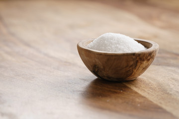 extra sea salt in wood bowl on wooden table, with copy space