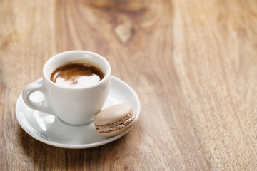 cup of fresh espresso with macaron on wood table with copy space