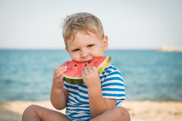 Caucasian boy eating watermelon on beach