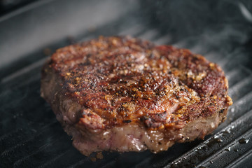 beef rib eye steak on grill pan closeup, shallow focus