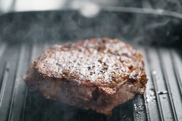 beef rib eye steak on grill pan closeup, shallow focus