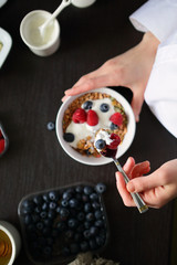 Breakfast healthy fresh raspberries, blueberries, sour cream, granola in hands
