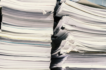 The stack of paper lay on a messy table in the office in the storage room.