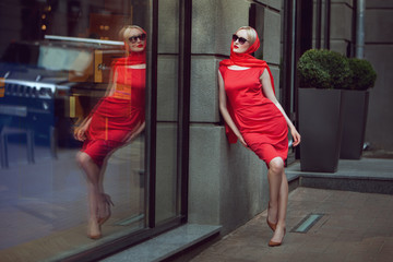 Fashionable woman admires herself in the reflection of the shop window.