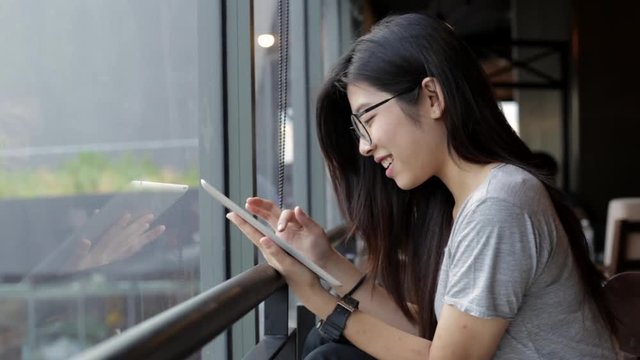 Young asian teenage woman sitting enjoy using tablet in coffee cafe for connect social community online, technology lifestyle