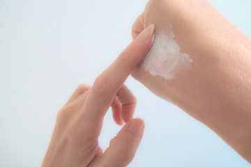 Close-Up Woman Hand Applying Moisturizing cream on White Background