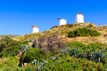Fototapeta na wymiar Three traditional windmills in Tripodes also known as Vivlos, one of the largest and most picturesque villages in southwestern Naxos. Cyclades Islands. Greece.