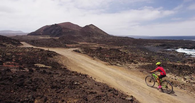 Mountain biking MTB cyclist woman and man cycling on bike trail path. Mountain biker couple on bike in riding bicycle enjoying healthy active lifestyle in nature, Lanzarote, Canary Islands, Spain