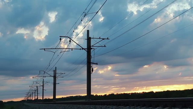 High-voltage network over the railway track on a cloudy sky background