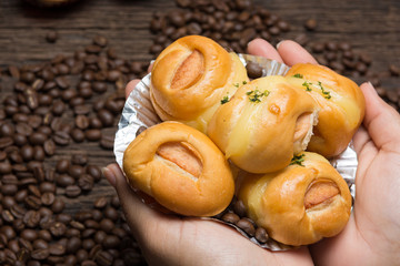 sausage bread in hands with coffee beans background