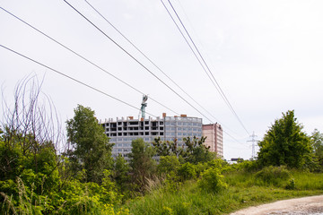 Fototapeta na wymiar Construction of new house or building. General view. Unfinished cement building in the summer. The introduction of urbanization into nature. Capital construction in Ukraine