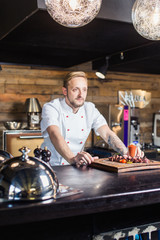 Chef leaning on the counter with a dish in a commercial kitchen