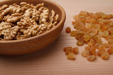 Walnuts in bowl and raisin on wooden background