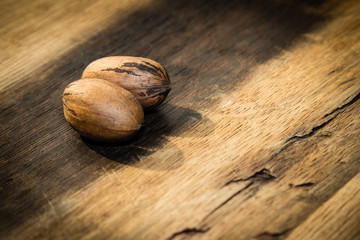 An organic food image consisting of two pecan nuts on a wooden background. 