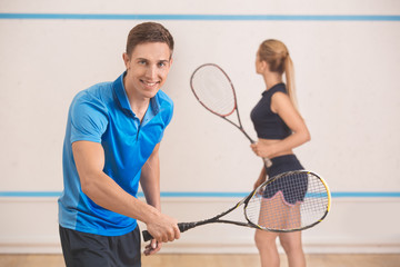 Young man and woman play squash in the gym