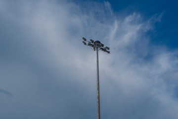 Obraz premium Large tall high outdoor stadium halogen spotlight with lamp light on and sky clouds