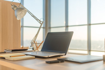 Side view picture of studio workplace with blank notebook, laptop. Comfortable work table, home office.
