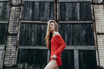 Fototapeta premium The sexy girl in red sweater about a wall