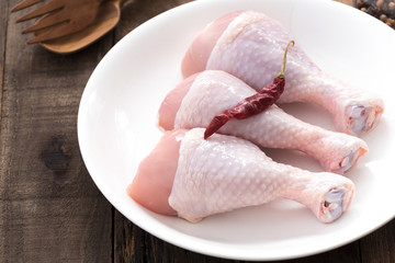 raw drumstick chicken on white plate

