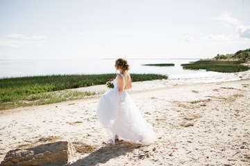 Fototapeta na wymiar bride in a wedding dress is walking along the beach.