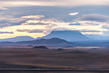 Vast landscape of Iceland, with a distance view of a peak covered by  clouds