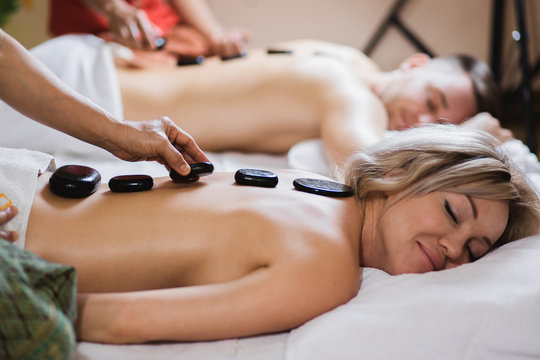 Couple enjoying a hot stone massage in a spa where heated stones are placed along the spine to relax the muscles
