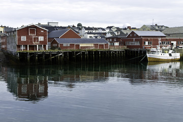 Fototapeta na wymiar Dock and buildings along the harbor of the fishing vilage Vardo, Norway