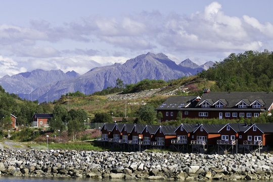Homes on the rock coastline of   Stokmarknes, Norway, with mountains in rear