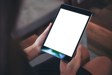 Mockup image of woman's hand holding black tablet pc with blank white screen in wooden cafe