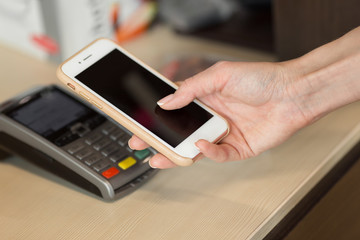 Close-up of woman making payment through NFC in cafeteria