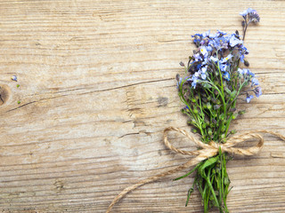 Forget me nots flowers with ribbon on a dark wooden background, copy space